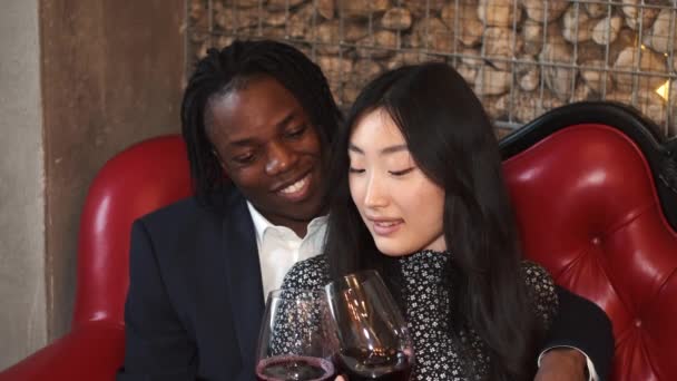 Liefdevol multi-etnisch paar drinken wijn op romantische date in restaurant — Stockvideo
