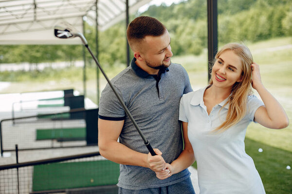Красивая пара играет в гольф на поле для гольфа