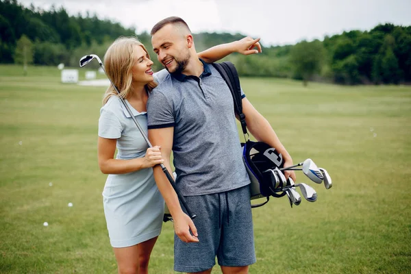 Vackra par spelar golf på en golfbana — Stockfoto