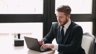 Laptop ve kağıtlarla bir kafede çalışan odaklanmış bir işadamı.