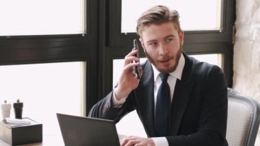 Laptop ve kağıtlarla bir kafede çalışan odaklanmış bir işadamı.