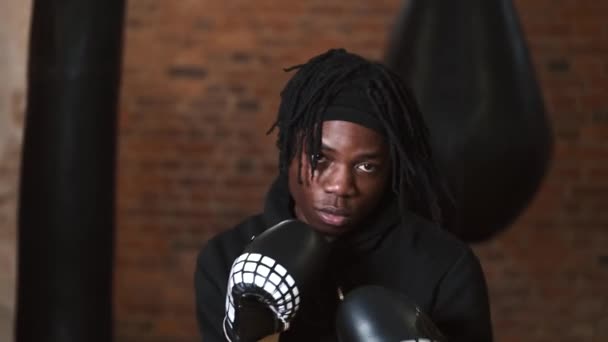 Dedikerad ung man som slår boxningssäck på gymmet — Stockvideo