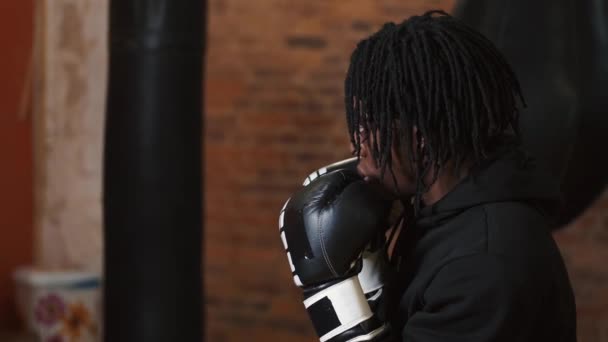 Dedikerad ung man som slår boxningssäck på gymmet — Stockvideo