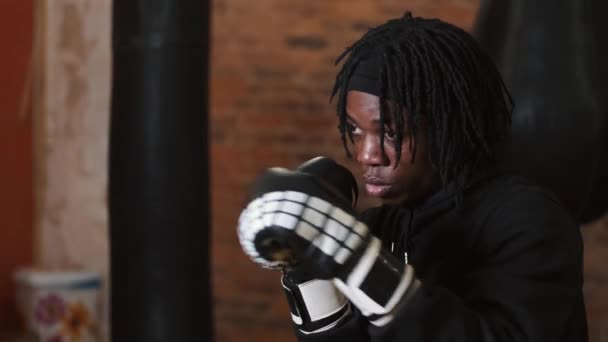 Jeune homme dédié punching sac de boxe à la salle de gym — Video