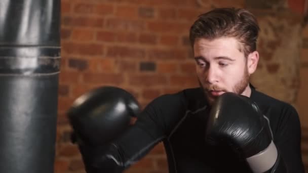 Dedikerad ung man som slår boxningssäck på gymmet — Stockvideo