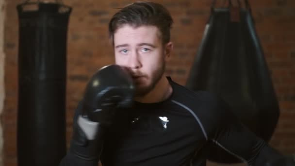 Dedikerad ung man som slår boxningssäck på gymmet — Stockvideo