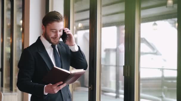 Allvarligt snyggt klädd man talar via telefon och arbetar på café — Stockvideo