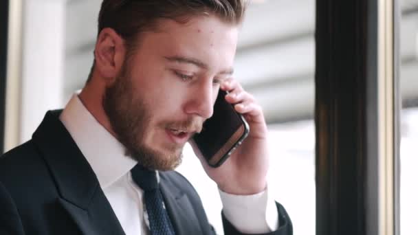 電話で話をしながらカフェで働く真剣なスマートな服装の男 — ストック動画
