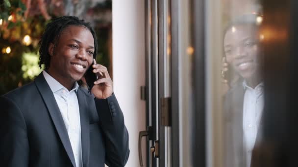 Serieuze slim geklede man die telefonisch praat en in café werkt — Stockvideo