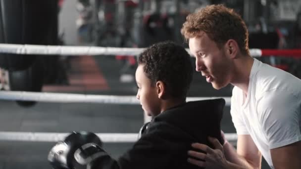 Boxer garçon pratiquant des coups de poing avec son entraîneur à la salle de gym — Video