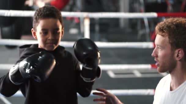 A fiú bokszoló az edzőjével gyakorolja az ütéseket az edzőteremben. — Stock videók