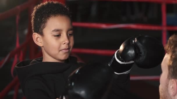 Boxer garçon pratiquant des coups de poing avec son entraîneur à la salle de gym — Video