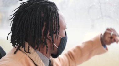 Maskeli Afrikalı Amerikalı öğrenci toplu taşıma araçlarını kullanıyor.