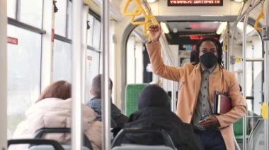 Maskeli Afrikalı Amerikalı öğrenci toplu taşıma araçlarını kullanıyor.