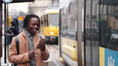 Otobüs durağında beklerken Afrikalı öğrenci telefonda konuşuyor.