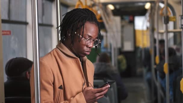 Afroamericano chico en cadual ropa uso teléfono en público transporte — Vídeos de Stock