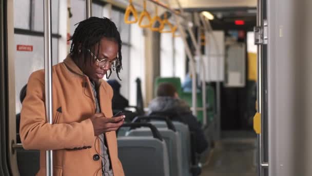 Afroamerikansk kille i kadualkläder använder telefon i kollektivtrafiken — Stockvideo