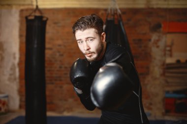 Spor salonunda siyah eldivenli bir erkek boksör.