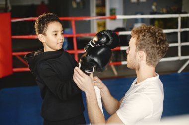 Boks eldivenli küçük çocuk antrenörüyle ringde.