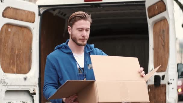 Leverancier die de goederen van de papieren doos buiten controleert — Stockvideo