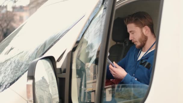Ο οδηγός παράδοσης ελέγχει τα χαρτιά στο φορτηγάκι του. — Αρχείο Βίντεο