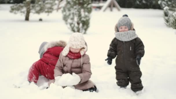 Crianças eu construindo um boneco de neve em um dia de inverno no quintal — Vídeo de Stock