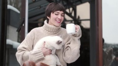 Huzurlu genç bayan kışın terasta çay içer.