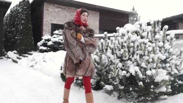 Snygg kvinna i päls och huvudduk på vintern bakgård — Stockvideo