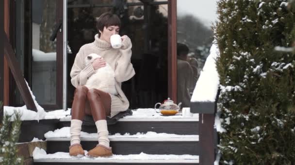 Pokojowa młoda kobieta pije zimą herbatę na tarasie. — Wideo stockowe