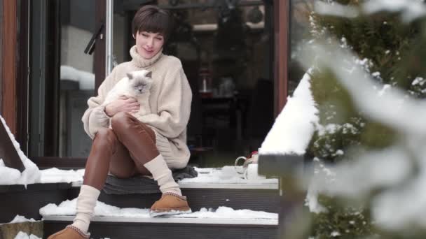 Мирная молодая женщина пьет чай на домашней террасе зимой — стоковое видео