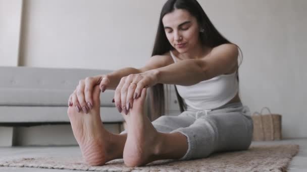 Jeune fille brune sportive ajustement avec queue de cochon, fait des exercices sur le tapis dans une pièce lumineuse — Video