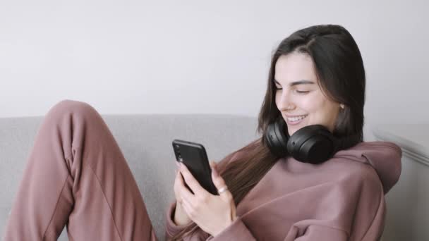 Jonge vrouw in hoofdtelefoon die thuis naar muziek luistert — Stockvideo