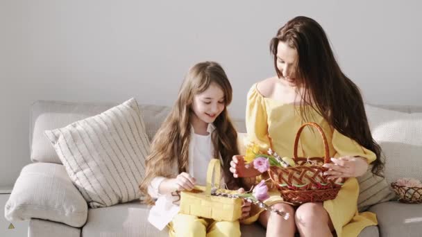 Mooie jonge moeder in gele jurk zitten met kinderen op coach op Pasen — Stockvideo