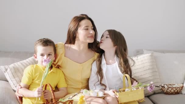 Pretty młoda matka w żółtej sukience siedzi z dziećmi na trenera na Wielkanoc — Wideo stockowe