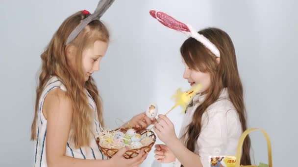 Two girls friends in bunny ears holding Easter eggs on holiday — Stock Video