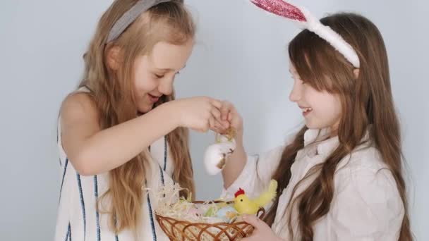 Twee meisjes vrienden in konijnenoren met paaseieren op vakantie — Stockvideo