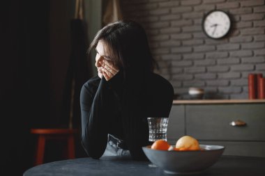 Mutfakta ağlayan siyah kazaklı depresif kadın.