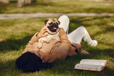 Kahverengi ceketli esmer pug 'la yürüyor.