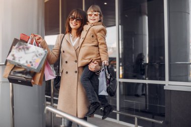 Şehirde alışveriş çantalı bir anne ve kız.