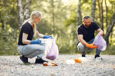 Bir çift parkta çöp poşetlerinde çöp topluyor.