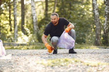 Bir çift parkta çöp poşetlerinde çöp topluyor.