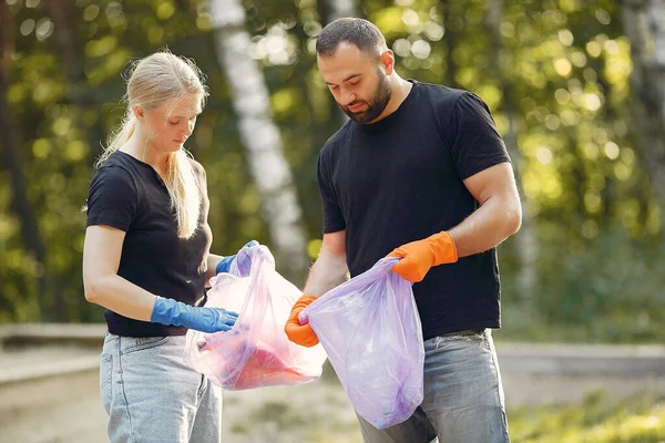 Couple collects garbage in garbage bags in park