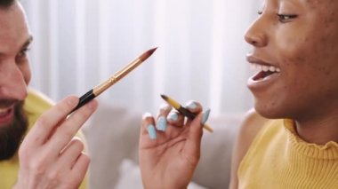 Siyah kadın ve Avrupalı erkek Paskalya yumurtalarını birlikte boyuyor.