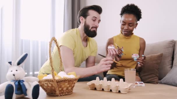 Zwarte vrouw en Europese man schilderen paaseieren samen — Stockvideo