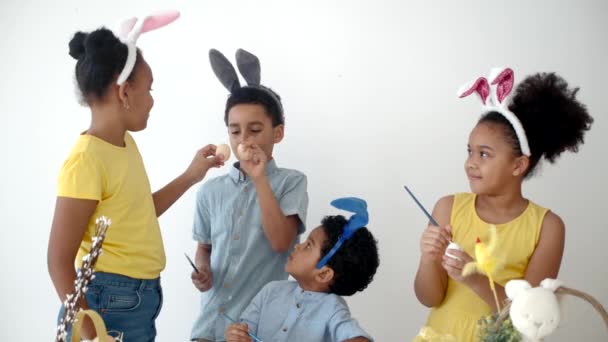 Африканские американские дети в смешных кроличьих ушах раскрашивают яйца на Пасху — стоковое видео