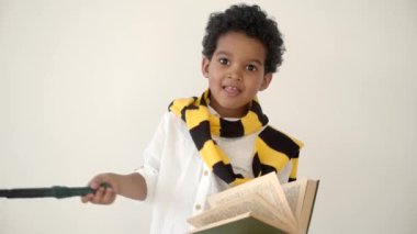 Afrikalı Amerikalı çocuk kitap okuyor ve sihirli değneği tutuyor.