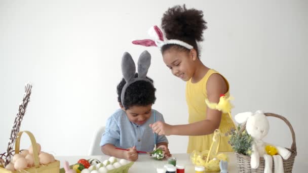 Enfants afro-américains dans des oreilles de lapin drôle colorant des œufs à Pâques — Video