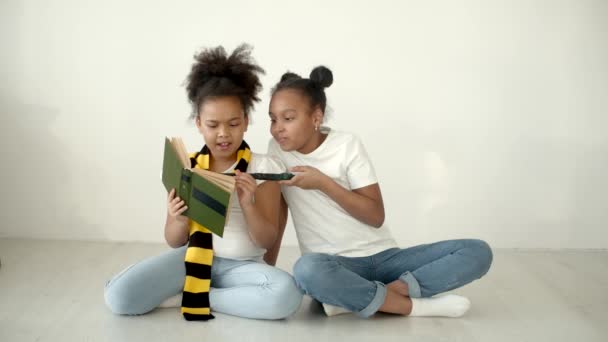 Afrikai amerikai lányok olvas egy könyvet, és kezében varázspálca — Stock videók