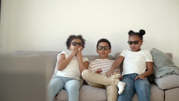 Милые дети в 3D очках смотрят кино на диване — стоковое видео