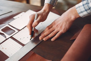 Stüdyodaki adam deri eşya üretiyor.